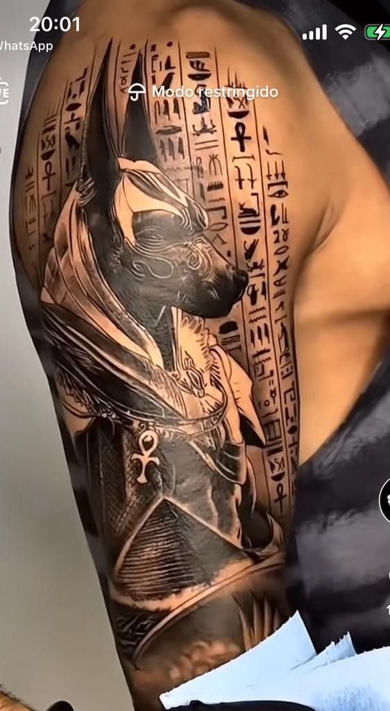 Hình xăm Anubis cổ điển trên vai, chi tiết tinh xảo, phong cách blackwork, độ phân giải cao.