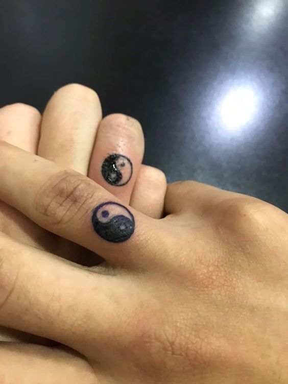 Hình xăm âm dương mini trên ngón tay, phong cách blackwork, chi tiết rõ nét.