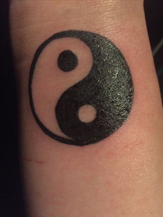 Hình xăm yin yang trên cổ tay, phong cách blackwork, chi tiết rõ nét.