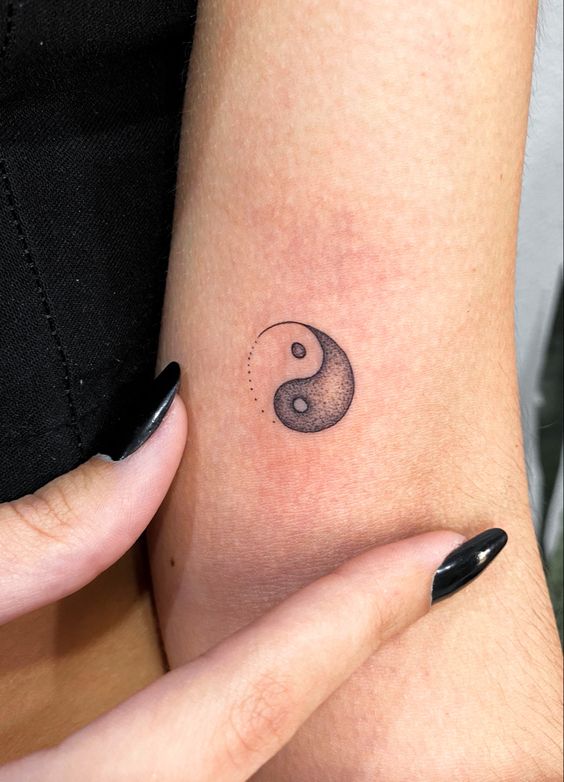 Hình xăm mini âm dương trên cánh tay, phong cách blackwork, chi tiết rõ nét, ảnh độ phân giải cao.