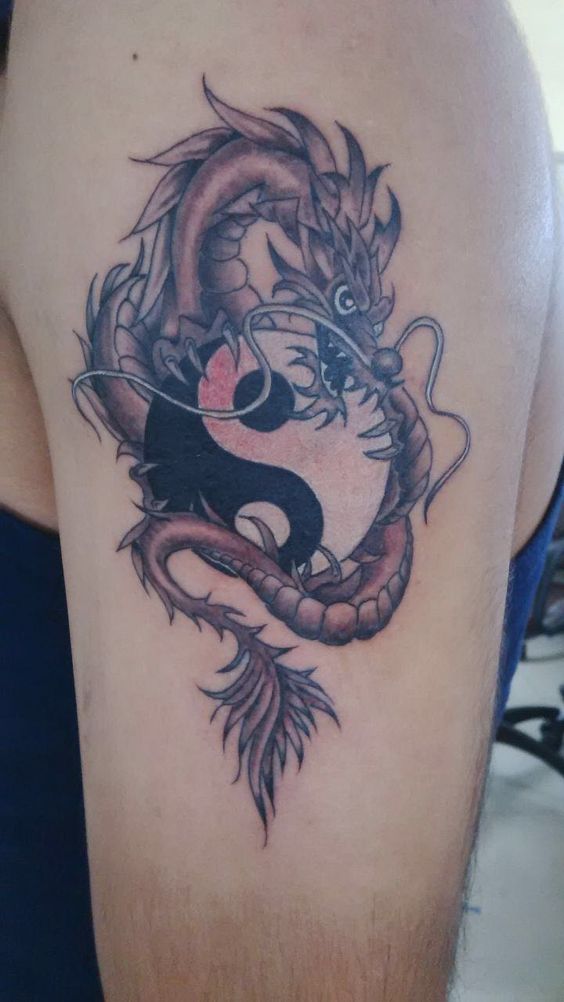 Hình xăm rồng và âm dương trên bắp tay, phong cách blackwork, chi tiết rõ nét, ảnh chất lượng HD.
