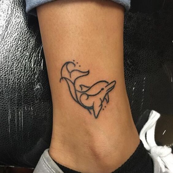 Hình xăm cá heo ở cổ chân Hình xăm cá heo mini trên mắt cá chân, phong cách blackwork, chi tiết đơn giản, độ phân giải HD.