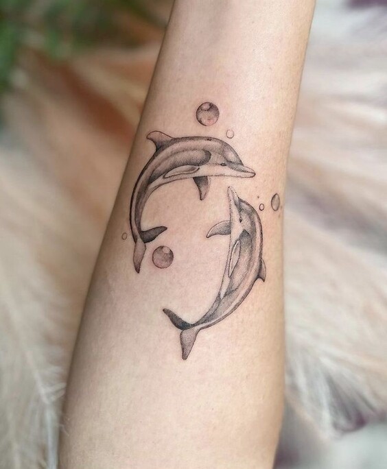 Hình xăm cá heo uyên ương Hình xăm cá heo trên cánh tay, phong cách blackwork, chi tiết tinh tế, ảnh HD.