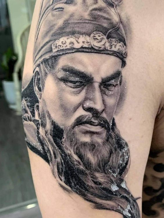 Hình xăm chân dung Quan Vũ trên tay Hình xăm chân dung cổ điển trên bắp tay, phong cách blackwork, chi tiết sắc nét, độ phân giải HD.
