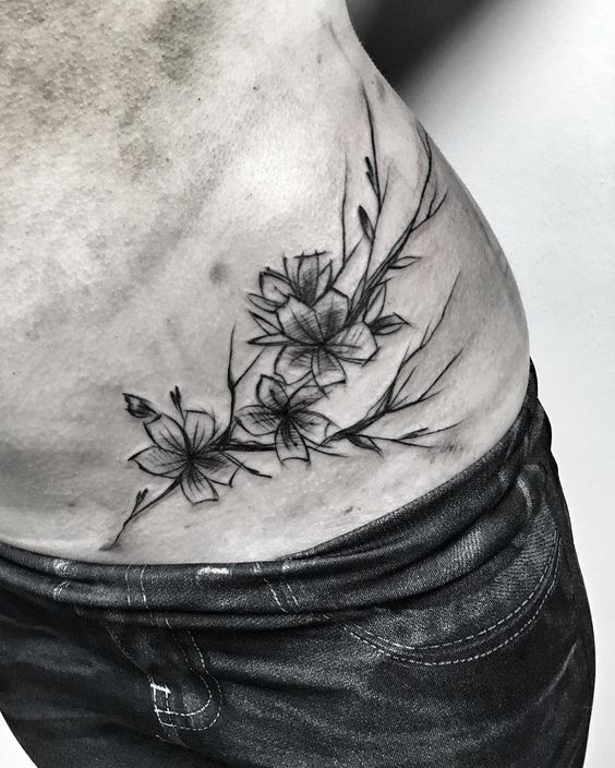 Hình xăm hoa đen trắng trên eo, phong cách blackwork, chi tiết rõ nét, ảnh độ phân giải cao.