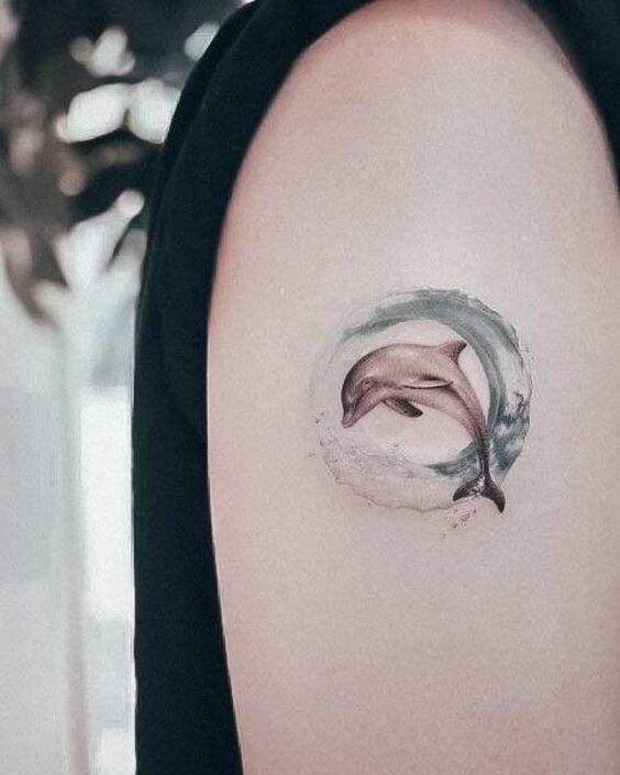 Hình xăm cho người thích phiêu lưu Hình xăm cá heo mini trên cánh tay, phong cách màu nước, chi tiết tinh tế, độ phân giải HD.