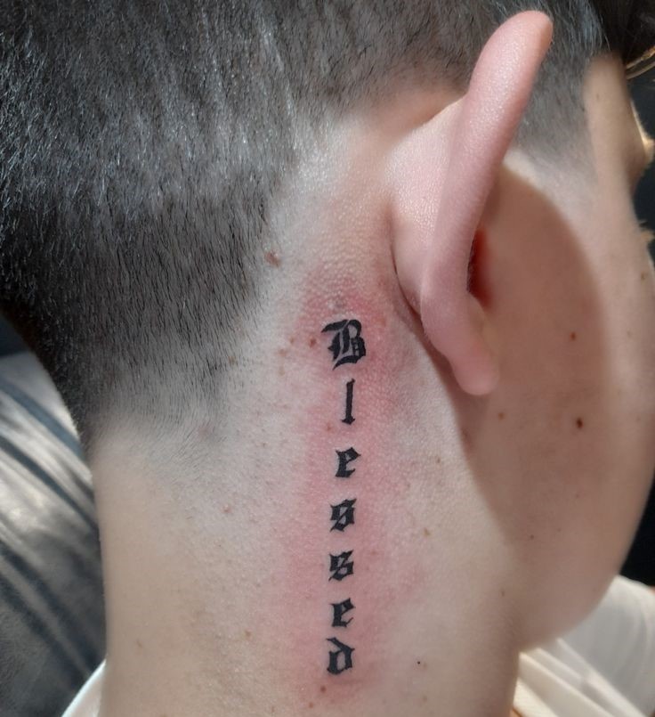 Hình xăm chữ "Blessed" sau tai, phong cách blackwork, chi tiết rõ nét, ảnh HD.