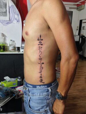 hình xăm chữ Trung Quốc dọc mạn sườn Hình xăm chữ Trung Quốc trên sườn, phong cách blackwork, chi tiết rõ nét, ảnh độ phân giải HD.