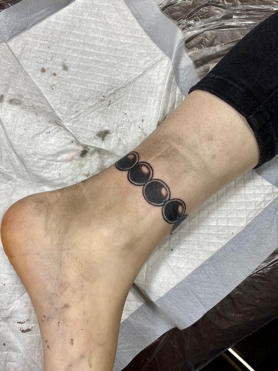 Hình xăm pha trăng mini ở mắt cá chân, phong cách blackwork, độ chi tiết cao, ảnh chất lượng HD.