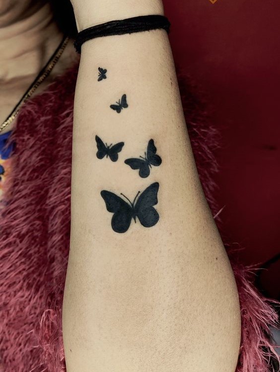 Hình xăm đàn bướm màu đen bay trên cổ tay Hình xăm bướm blackwork trên cánh tay, chi tiết đơn giản, ảnh HD.