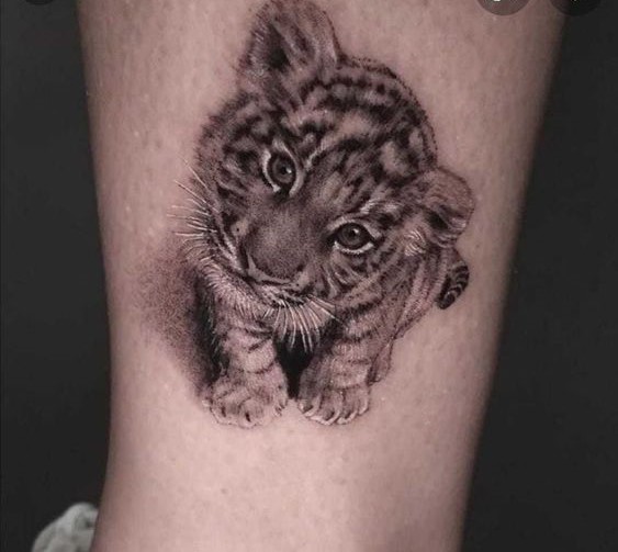 Hình xăm hổ con trên chân, phong cách blackwork, chi tiết rõ nét, độ phân giải HD.