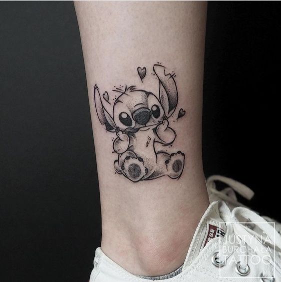 Hình xăm đen trắng nhân vật Stitch trên cổ chân Hình xăm Stitch dễ thương trên chân, phong cách blackwork, chi tiết, độ phân giải HD.