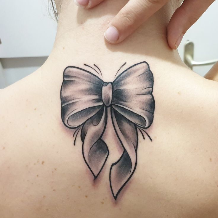 hình xăm đơn sắc trên lưng Hình xăm nơ cổ điển trên lưng, phong cách blackwork, chi tiết rõ nét, độ phân giải HD.