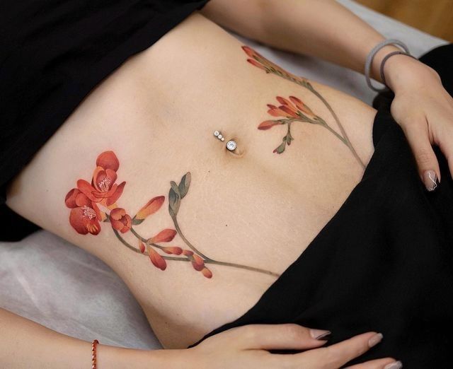 Hình xăm đối xứng hai bên eo Hình xăm hoa màu nước trên bụng, chi tiết tinh tế, phong cách tự nhiên, độ phân giải HD.