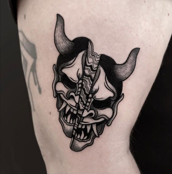Hình xăm mặt nạ quỷ phong cách blackwork trên bắp tay, chi tiết rõ nét, ảnh độ phân giải HD.