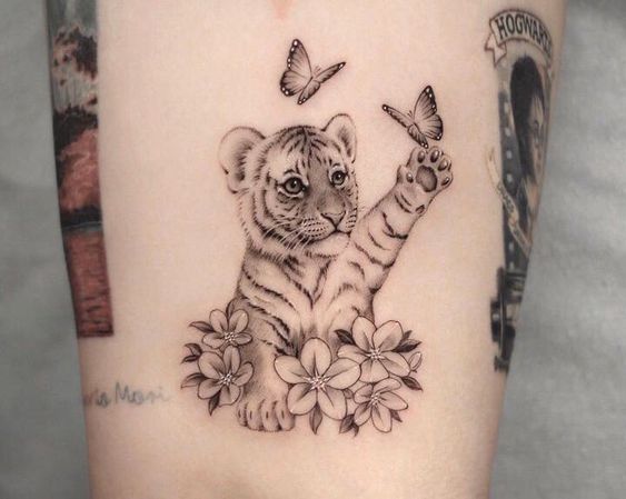 Hình xăm hổ con và bướm ở tay, phong cách blackwork, chi tiết cao, độ phân giải HD.