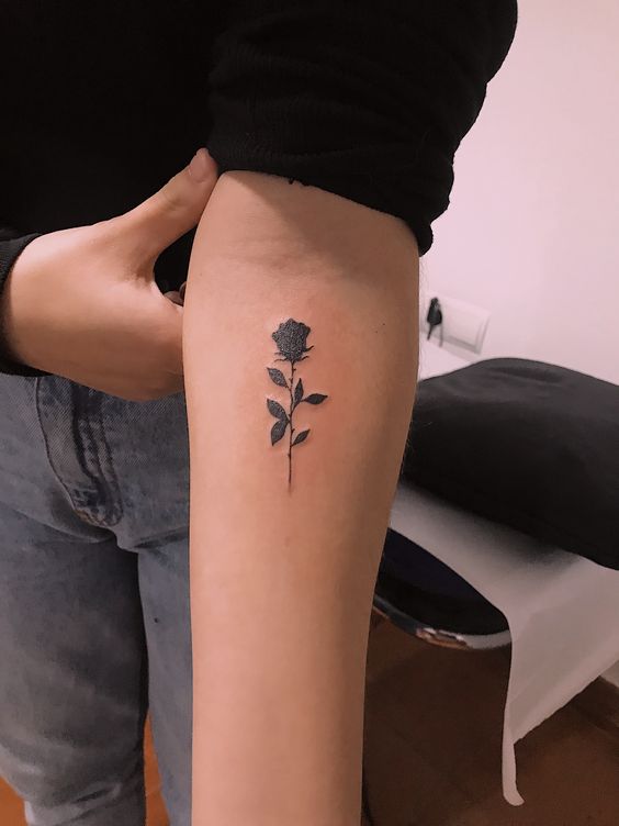 hình xăm hoa hồng đen mini dịu dàng cho nữ Hình xăm hoa hồng đen trên cánh tay, phong cách blackwork, chi tiết. Ảnh chất lượng HD.