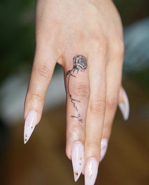 Mini tattoo of a black rose on the ring finger Hình xăm hoa hồng mini trên ngón tay, phong cách blackwork, hình ảnh chi tiết rõ nét HD.
