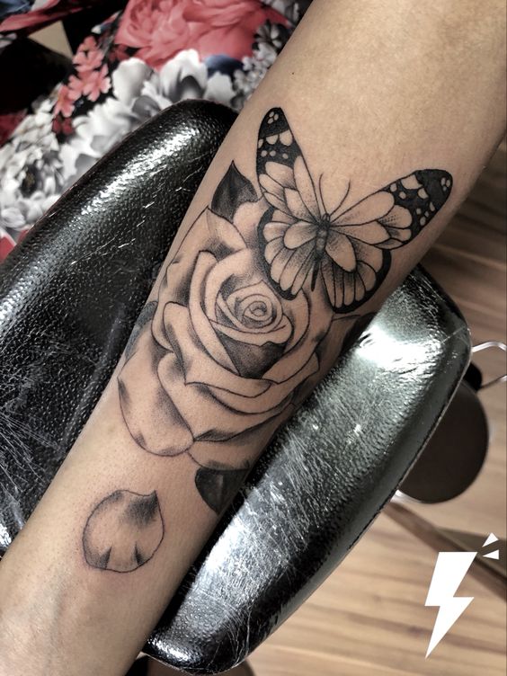 Hình xăm hoa hồng và bướm phong cách blackwork trên cánh tay, chi tiết sắc nét, ảnh chất lượng cao.
