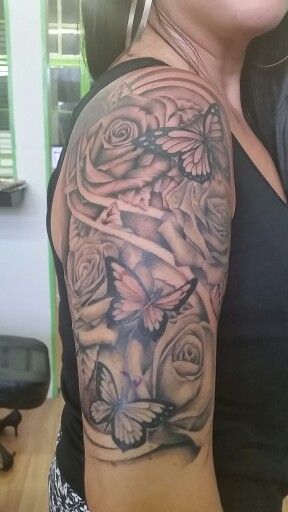 Hình xăm hoa hồng và bướm ở cánh tay, phong cách blackwork, chi tiết rõ nét, độ phân giải HD.