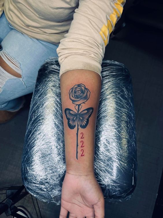 Hình xăm hoa hồng và bươm bướm trên cánh tay, phong cách blackwork, chi tiết rõ nét, ảnh HD.