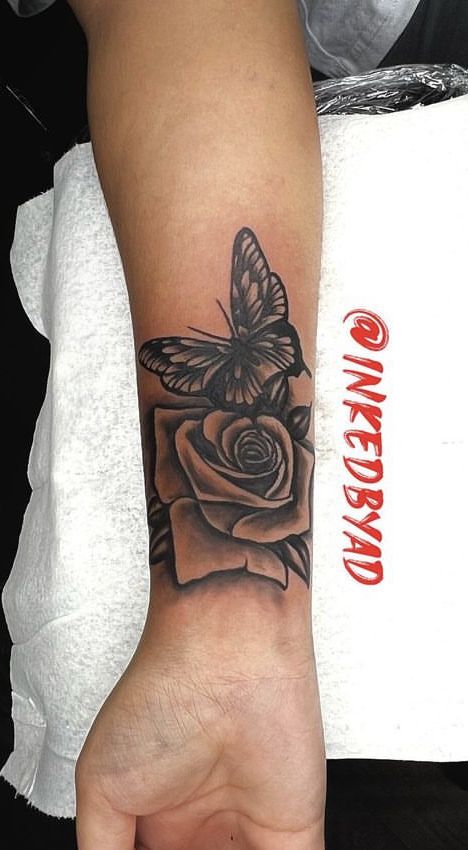 Hình xăm hoa hồng và bướm trên cánh tay, phong cách blackwork, chi tiết rõ nét, độ phân giải HD.