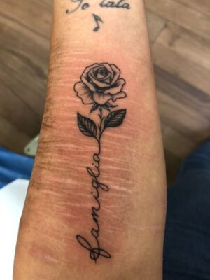 Hình xăm hoa hồng ở tay, phong cách blackwork, chữ "famiglia", chi tiết sắc nét, ảnh độ phân giải HD.