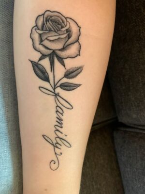 Hình xăm hoa hồng và chữ "family" trên tay, phong cách blackwork, chi tiết rõ nét, ảnh HD.