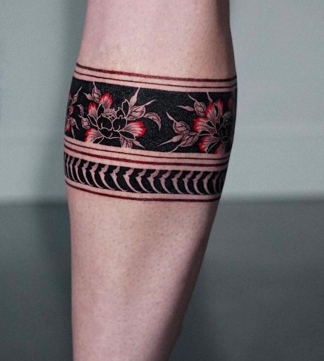 Hình xăm hoa văn đen đỏ trên bắp tay, phong cách blackwork, chi tiết sắc nét, độ phân giải HD.