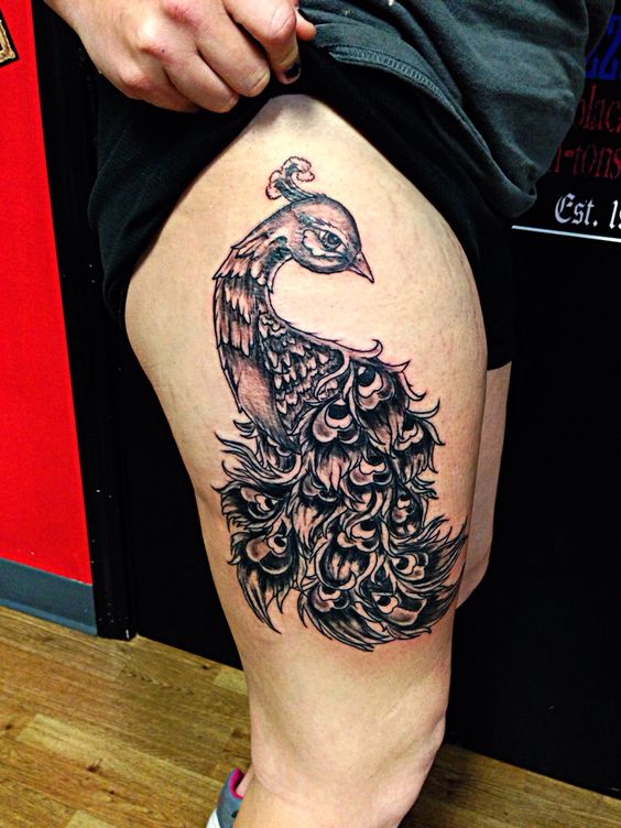 Hình xăm con công phong cách blackwork trên đùi, chi tiết sắc nét, độ phân giải HD.