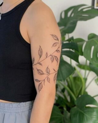 Hình xăm lá trên cánh tay, phong cách blackwork, chi tiết tinh tế, độ phân giải HD.