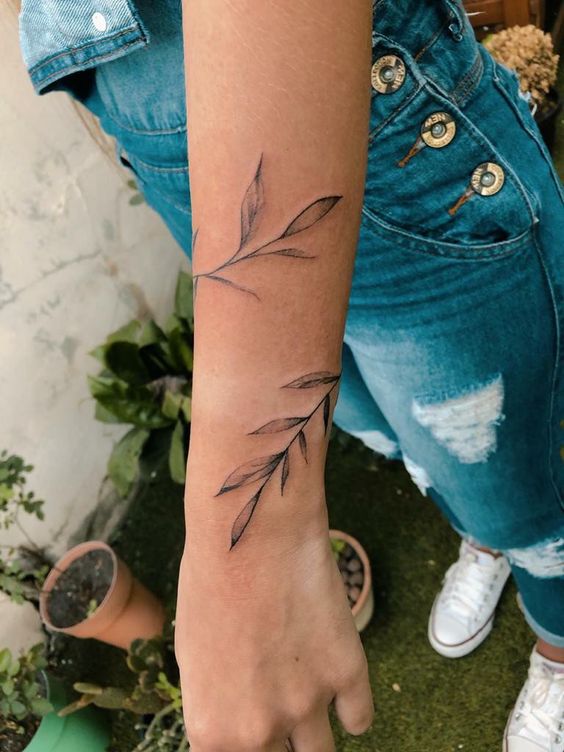Hình xăm cành lá trên cánh tay, phong cách blackwork tối giản, ảnh HD chi tiết.
