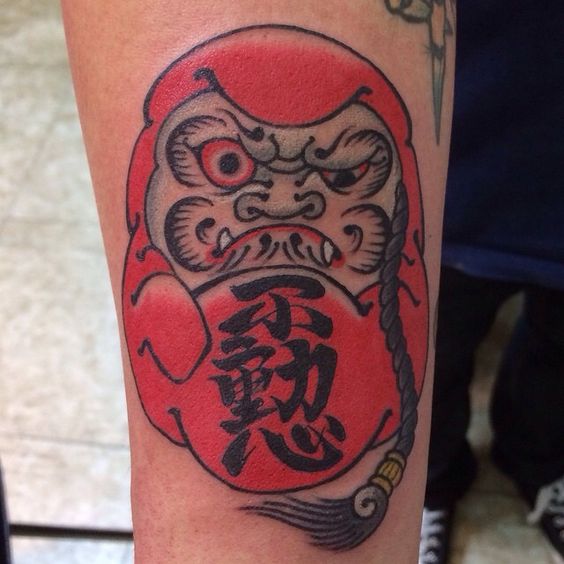 Hình xăm mặt Daruma xua tan xui xẻo theo yêu cầu khách hàng Hình xăm Daruma cổ điển trên cánh tay, phong cách truyền thống Nhật Bản, chi tiết rõ nét, ảnh HD.