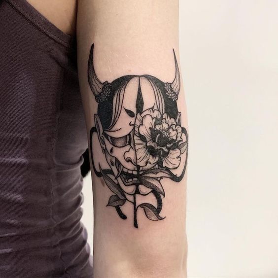 Hình xăm mặt nạ Oni và hoa trên cánh tay, phong cách blackwork, chi tiết rõ nét, độ phân giải HD.