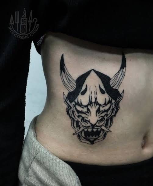 Hình xăm mặt nạ quỷ trên eo, phong cách blackwork, chi tiết rõ nét, độ phân giải HD.