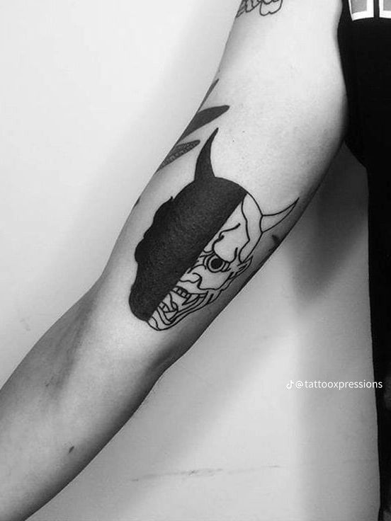 Hình xăm mặt nạ quỷ phong cách blackwork trên bắp tay, chi tiết sắc nét, ảnh HD.