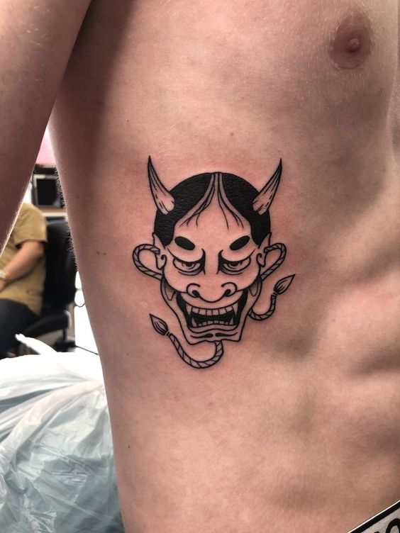 Hình xăm mặt nạ Oni trên sườn, phong cách blackwork, chi tiết sắc nét, độ phân giải HD.