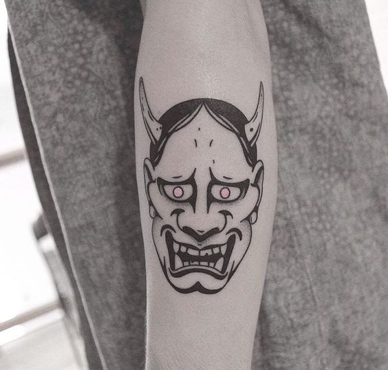 Hình xăm mặt nạ Oni trên tay, phong cách blackwork, chi tiết rõ nét, độ phân giải HD.