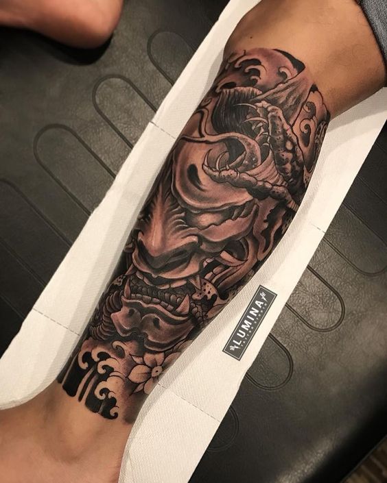 Hình xăm mặt nạ Oni trên chân, phong cách blackwork chi tiết, ảnh chất lượng HD.