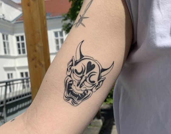 Hình xăm mặt nạ Oni trên cánh tay, phong cách blackwork, chi tiết rõ nét, độ phân giải HD.