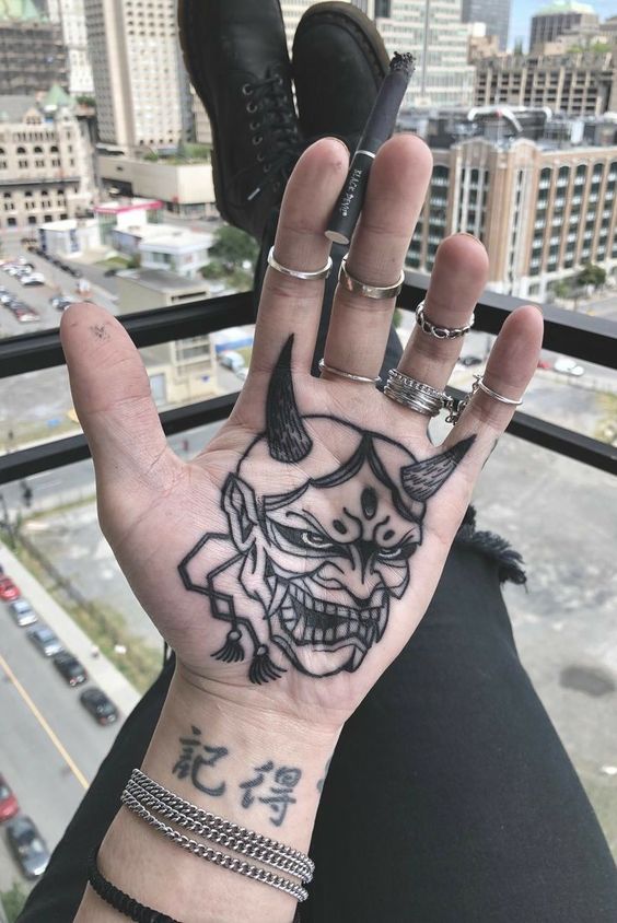 Hình xăm mặt nạ Oni trên lòng bàn tay, phong cách blackwork, chi tiết, ảnh độ phân giải cao.