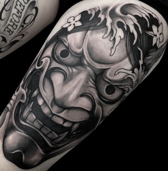 Hình xăm mặt nạ Oni trên bắp tay, phong cách blackwork chi tiết, độ phân giải HD.