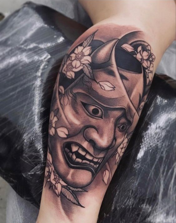 Hình xăm mặt nạ Oni trên bắp tay, phong cách blackwork chi tiết, hình ảnh chất lượng cao.