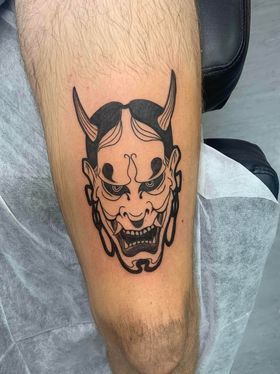 Hình xăm mặt quỷ phong cách blackwork trên bắp tay, chi tiết rõ nét, ảnh độ phân giải HD.