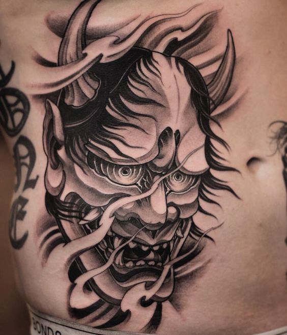 Hình xăm mặt quỷ phong cách blackwork ở bụng, chi tiết rõ nét, độ phân giải HD.