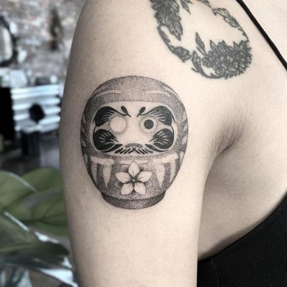 Hình xăm mặt tròn daruma siêu đáng yêu ở bắp tay cho chị khách Hình xăm Daruma trên bắp tay, phong cách blackwork, chi tiết rõ nét, độ phân giải HD.