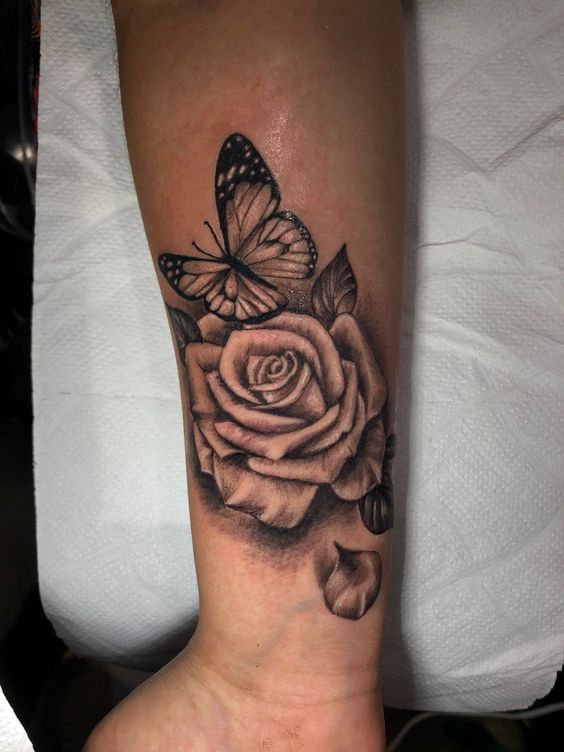Hình xăm hoa hồng và bướm trên cánh tay, phong cách blackwork, chi tiết cao, độ phân giải HD.