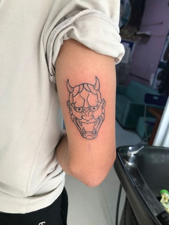 Hình xăm mặt nạ Oni trên cánh tay, phong cách blackwork, chi tiết, độ phân giải HD.