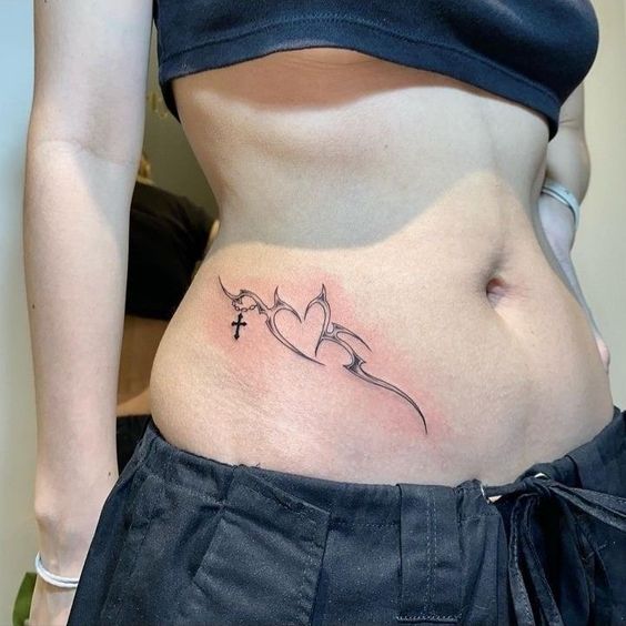 Hình xăm tribal trên hông với họa tiết trái tim và thánh giá, phong cách blackwork, ảnh HD.