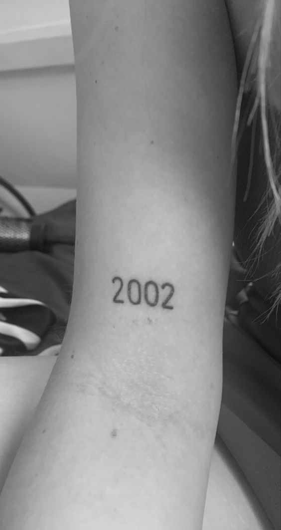 Hình xăm số "2002" trên tay, phong cách tối giản, đen trắng, độ phân giải HD.